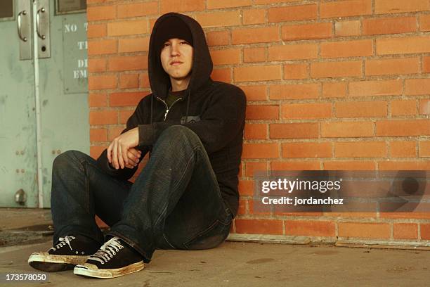 punk and a hoodie with dirty shoes sitting by brick wall - runaway stock pictures, royalty-free photos & images