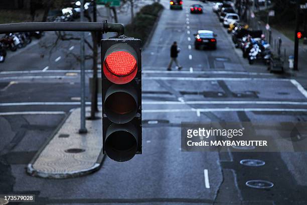 red light hanging above a paved street in the city - road intersection stock pictures, royalty-free photos & images