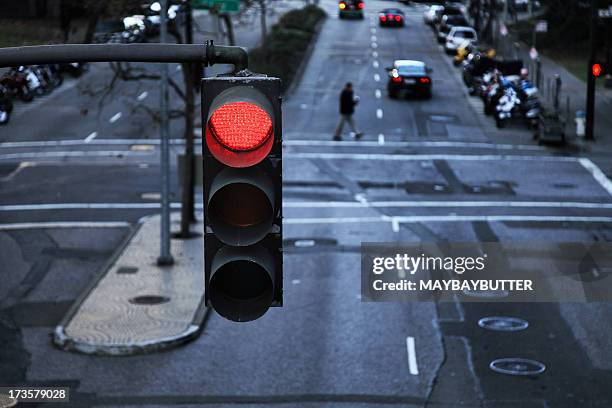 red light hanging above a paved street in the city - stoplight bildbanksfoton och bilder