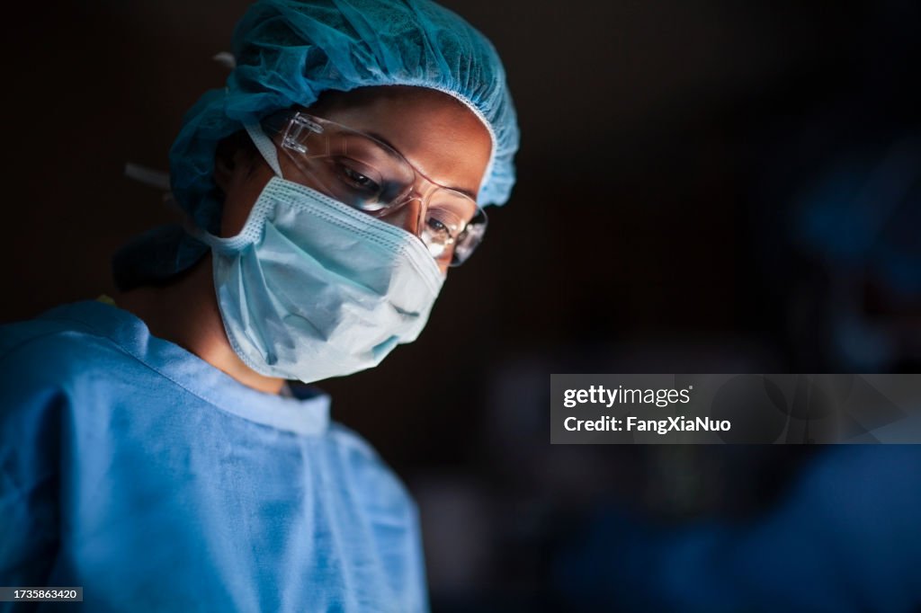 Hispanische Ärztin blickt auf den Patienten im Operationssaal der medizinischen Chirurgie im Krankenhaus herab