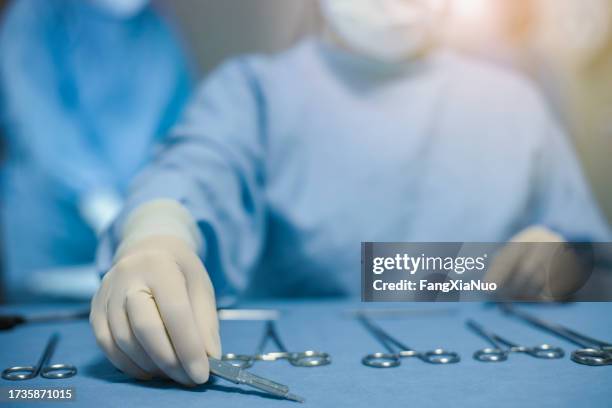 main de l’infirmière préparant l’arrangement des outils chirurgicaux médicaux sur le plateau portant des gants en latex vêtements de travail de protection pour la sécurité dans la salle d’opération chirurgicale à l’hôpital avec l’infirmi - scalpel photos et images de collection