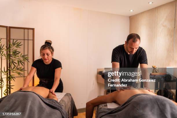 couple enjoying a massage in a spa - massage room fotografías e imágenes de stock