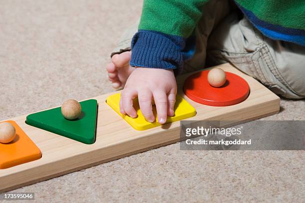 baby learning to play using large wooden puzzle pieces - baby toy stock pictures, royalty-free photos & images