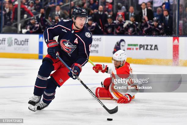 Zach Werenski of the Columbus Blue Jackets skates the puck away from A.J. Greer of the Calgary Flames during the first period of a game at Nationwide...