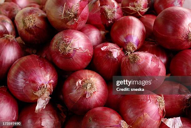 a pile of red onions as a background - red onion stockfoto's en -beelden