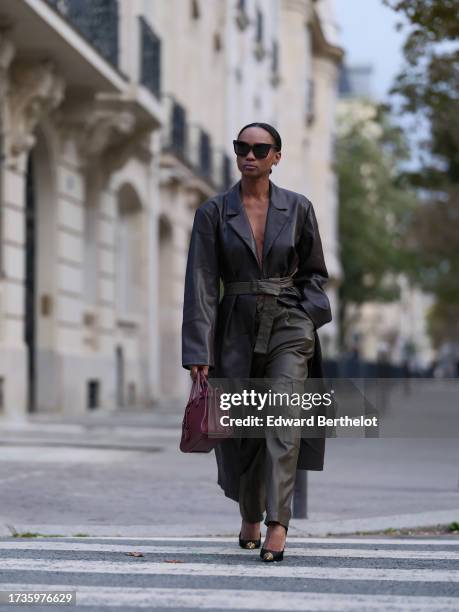 Emilie Joseph @in_fashionwetrust wears a kaki and brown leather set, a cinched Dark brown Vintage Tailored Extra long leather coat, kaki green cargo...