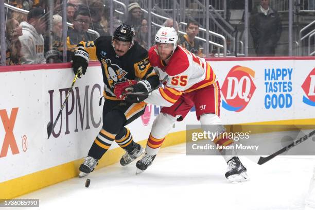 Matt Nieto of the Pittsburgh Penguins and Noah Hanifin of the Calgary Flames battle for the puck along the boards during the first period at PPG...