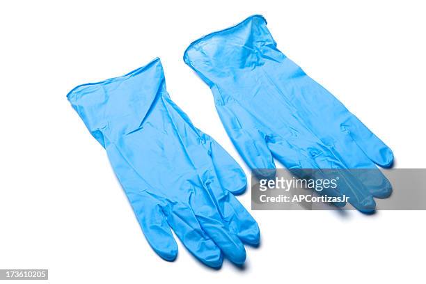 pair of blue surgical gloves laying on white background - surgical glove stock pictures, royalty-free photos & images