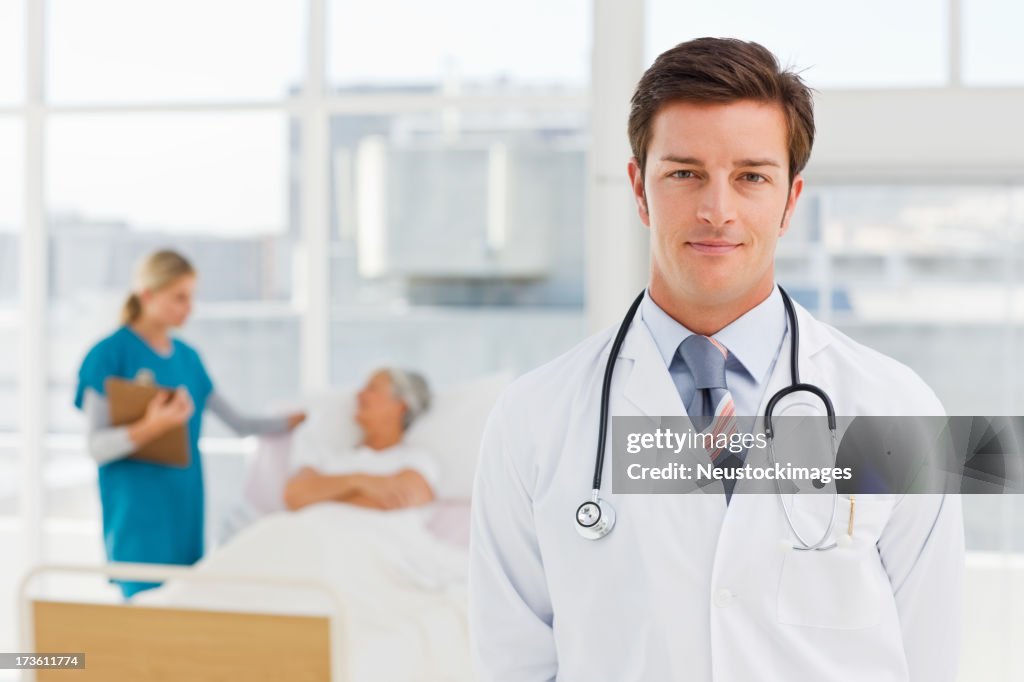 Young doctor with nurse and patient in the background