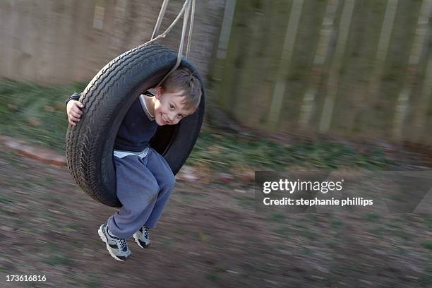 young boy playing outside in a tire swing - tire swing stock pictures, royalty-free photos & images