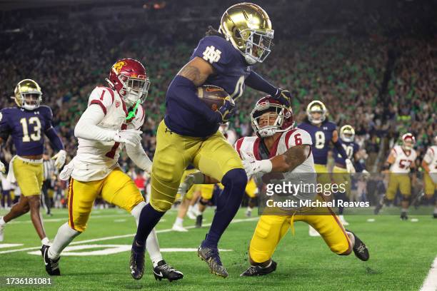 Xavier Watts of the Notre Dame Fighting Irish stiffs arms Austin Jones of the USC Trojans after intercepting a pass from Caleb Williams during the...