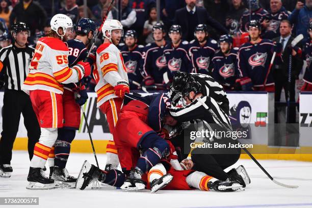 The linesmen break up a scuffle between Erik Gudbranson of the Columbus Blue Jackets and Jonathan Huberdeau of the Calgary Flames during the third...