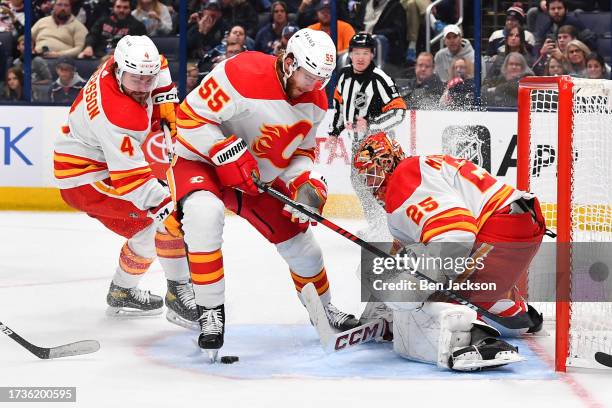 Goaltender Jacob Markstrom of the Calgary Flames defends the net as Rasmus Andersson and Noah Hanifin of the Calgary Flames follow a loose puck...