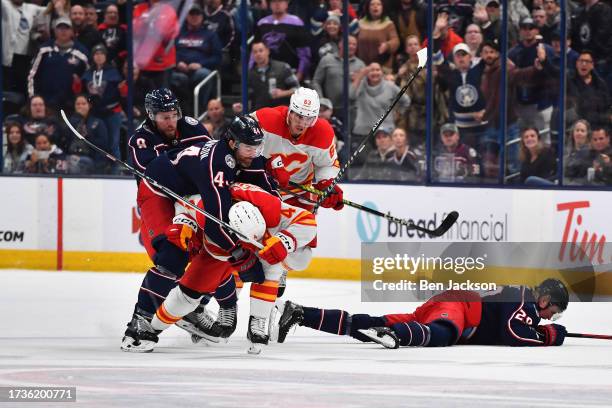 Rasmus Andersson of the Calgary Flames is tackled by Erik Gudbranson of the Columbus Blue Jackets after hitting Patrik Laine of the Columbus Blue...