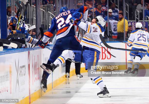 Dylan Cozens of the Buffalo Sabres checks Scott Mayfield of the New York Islanders during the third period at UBS Arena on October 14, 2023 in...