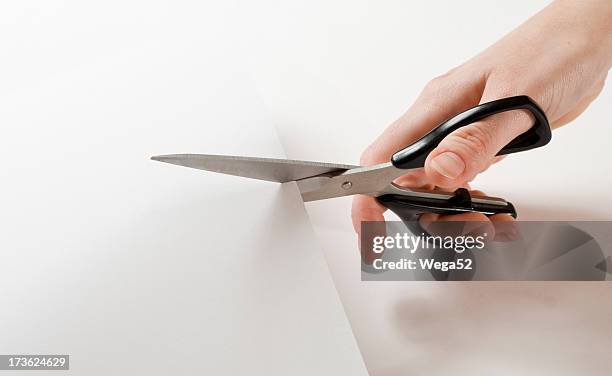 close up of hand holding scissors and cutting through paper - sax bildbanksfoton och bilder