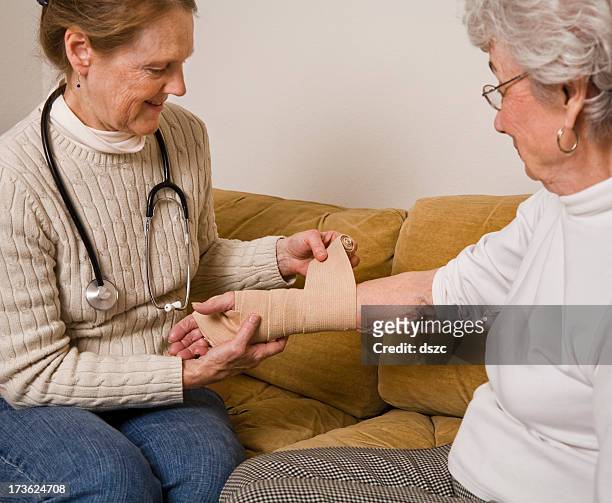 home healthcare nurse wraps bandage on wrist of senior woman - elastic bandage stock pictures, royalty-free photos & images