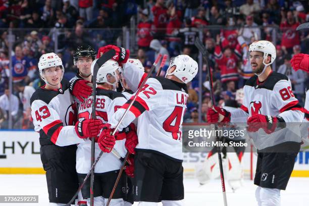 Jack Hughes of the New Jersey Devils is congratulated by his teammates after scoring the game-winning goal against the New York Islanders during...
