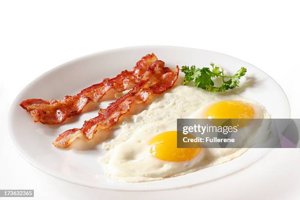 two eggs over easy with bacon on white plate - stekt ägg bildbanksfoton och bilder