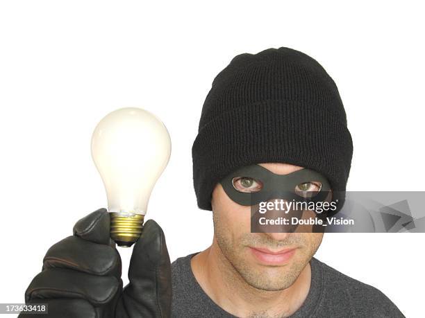 intellectual property theft: masked bandit in black holds a lightbulb - stealing idea stock pictures, royalty-free photos & images