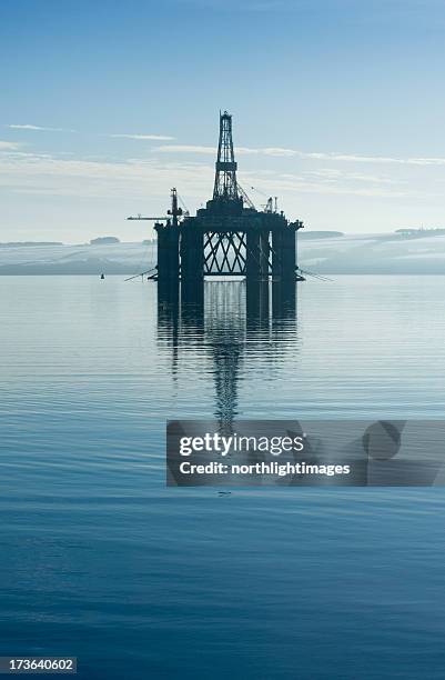 an oil rig in the middle of a body of water  - boortoren stockfoto's en -beelden