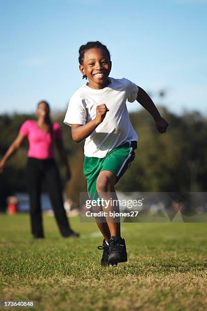 child running on grass while mother watches - running boy stock pictures, royalty-free photos & images