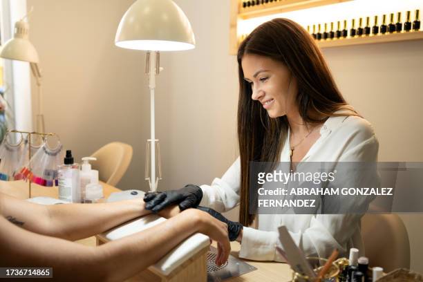 worker massaging hands after a manicure treatment in a salon - artificial nails stock pictures, royalty-free photos & images