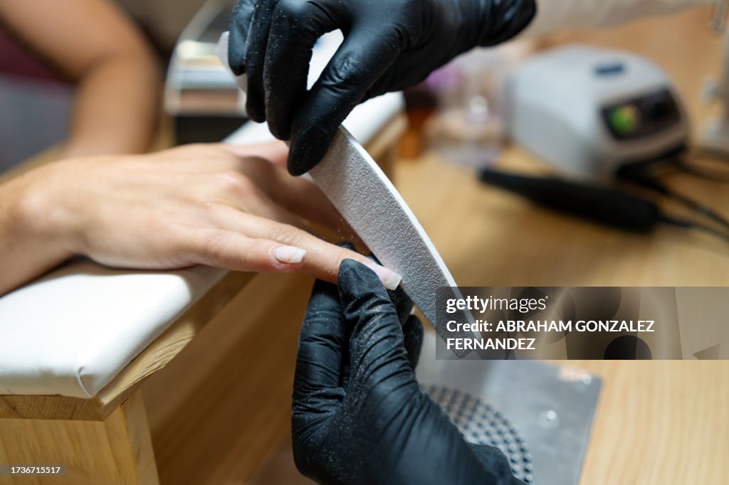 Técnico puliendo las uñas de un cliente usando una lima