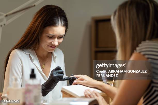 blonde woman having nails done in salon - artificial nails stock pictures, royalty-free photos & images