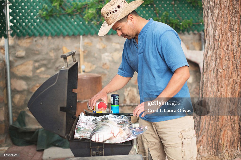 Man Grilling Fish Outdoors on Grill