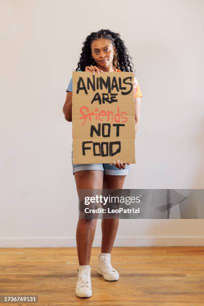 frau zeigt ein banner gegen tierquälerei und wirbt für veganismus - vegetarisch gerecht stock-fotos und bilder