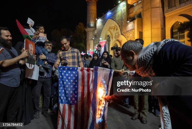 An Iranian protester burn the U.S. Flag and an Israeli flag in a rally protesting the Israeli attacks on Gaza city, at the Palestine square in...