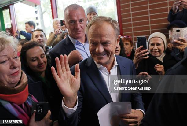 Donald Tusk, co-leader of Civic Coalition, a center-left pro-European political coalition, greets supporters as he departs from a polling station...