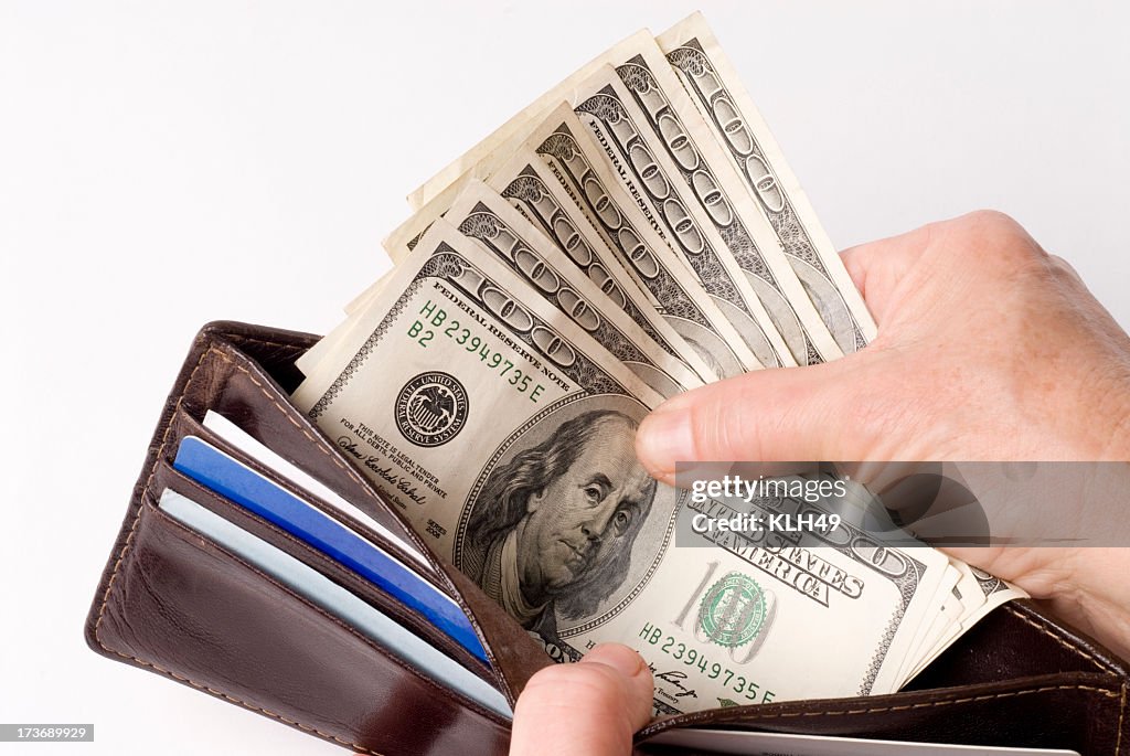 Hands spreading open a wallet, showing 5 100 dollar bills