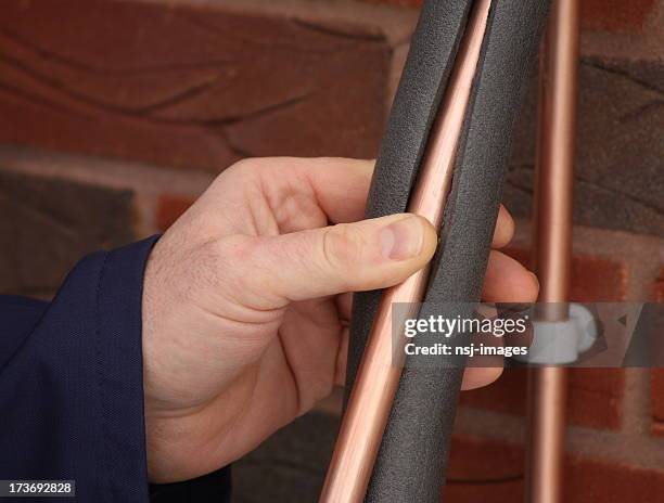 plumber insulating a copper water pipe - insulator stock pictures, royalty-free photos & images