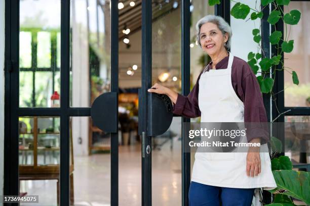 we're ready to serve you. every menu has quality for you. an asian senior woman owner in front of the front store opening her restaurant to serve a customer. local restaurant business concepts. - franchising stock pictures, royalty-free photos & images