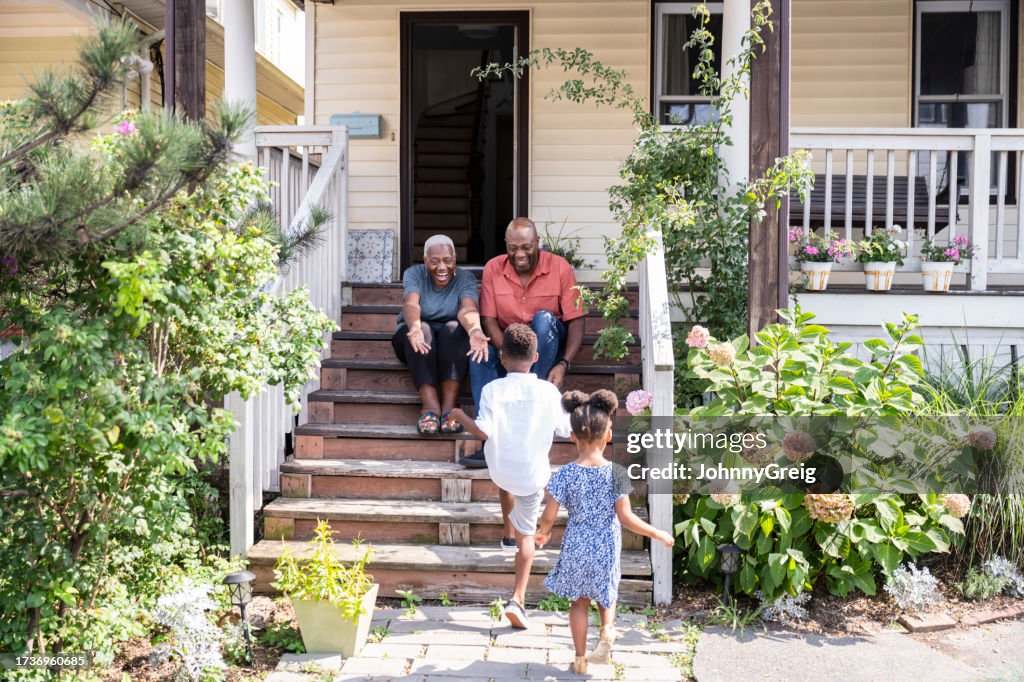 Happy Black seniors welcoming visiting grandchildren