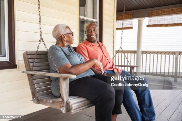 retired black seniors sitting together on porch swing - swing chair stock pictures, royalty-free photos & images