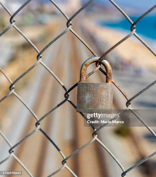 old padlock er fence on a railroad track - eternidad fotografías e imágenes de stock