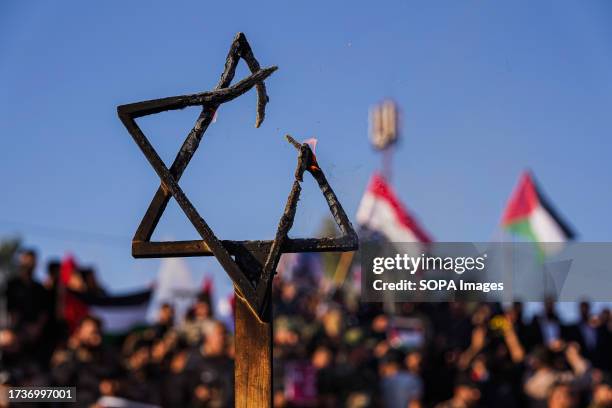 Man holds a burning Star of David during a protest. Hundreds of supporters of the Iraqi Shi'ite Popular Mobilization Forces gathered to protest...