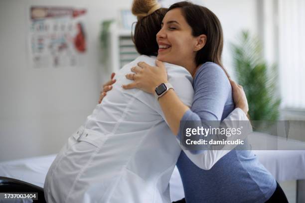 shot of a pregnant woman hugging her doctor during a consultation - pregnant women greeting stockfoto's en -beelden