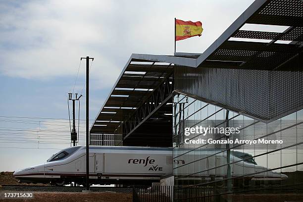 An AVE, the Spanish high speed train, enters to the Villena glass-and-steel station coming from Alicante as a Spanish flag flutters crowning the...