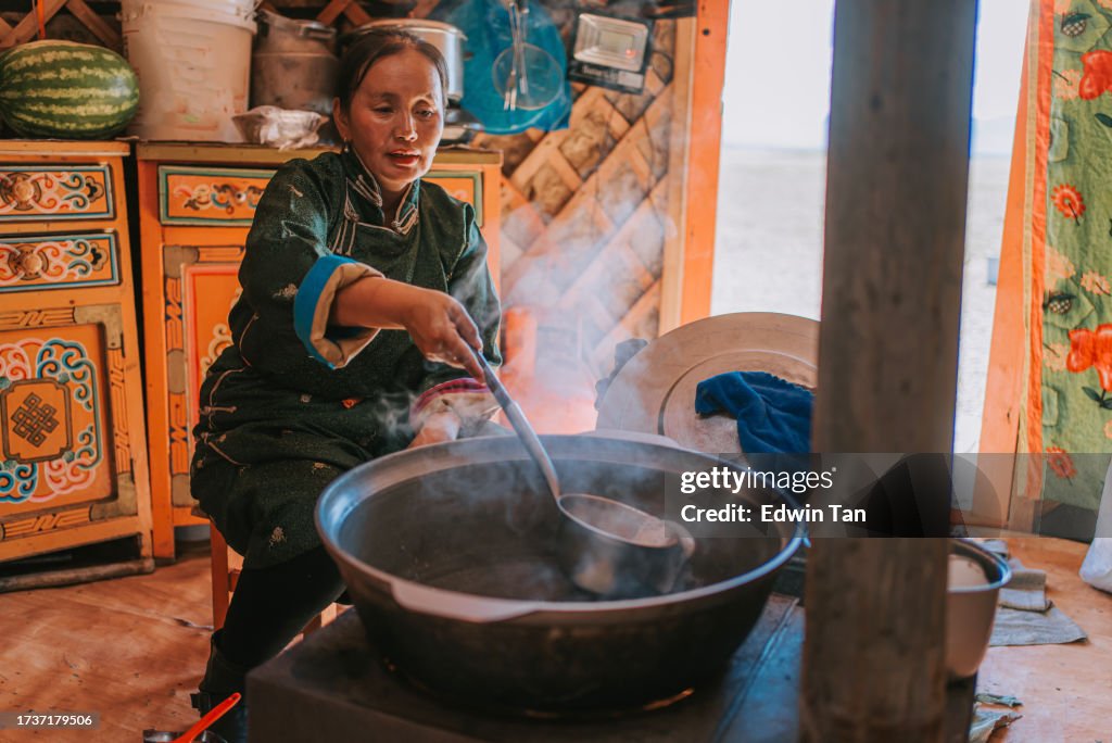 Mongolian nomad woman preparing traditional milk tea for guest inside Ger