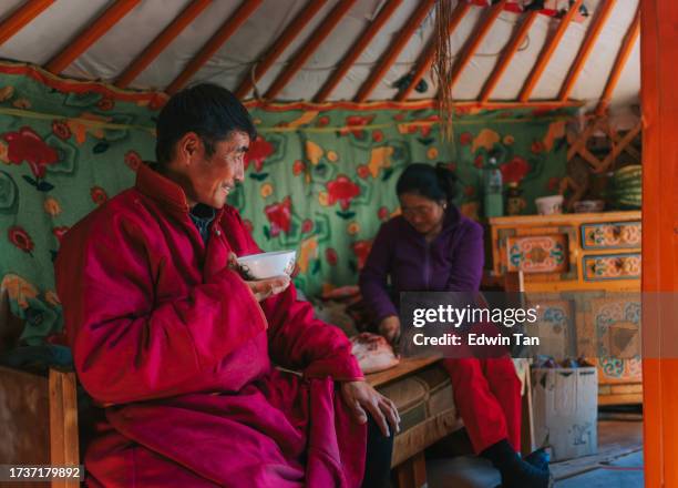 mongolian man enjoying goat milk tea inside yurt with his family - mongolië stockfoto's en -beelden