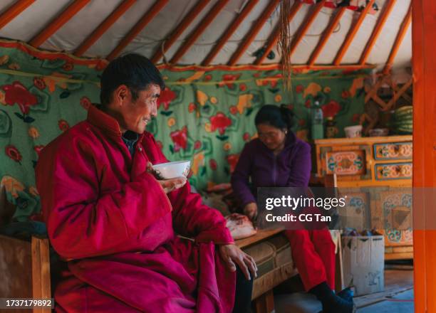 mongolian man enjoying goat milk tea inside yurt with his family - independent mongolia stock pictures, royalty-free photos & images