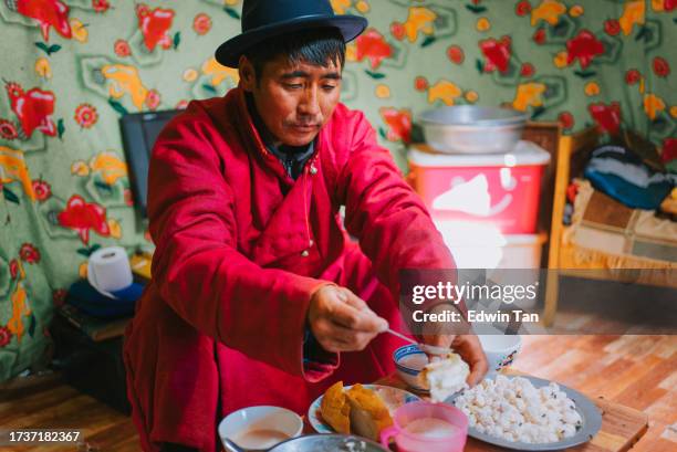 mongolian man enjoying breakfast homemade butter with bread in yurt - mongolsk kultur bildbanksfoton och bilder