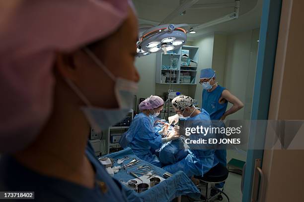 Photo taken on July 12, 2013 shows doctors and nurses performing a cosmetic rhinoplasty procedure at the JK Medical Group plastic surgery hospital in...