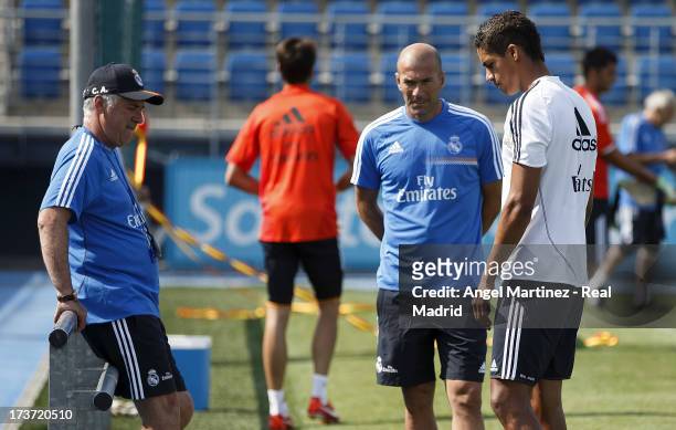 Raphael Varane of Real Madrid talks with head coach Carlos Ancelotti and assistant Zinedine Zidane during a training session at Valdebebas training...