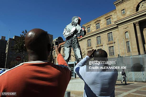 Men takes pictures of the statue of former South African President Nelson Mandela as a boxer in downtown on Johannesburg on July 17, 2013. Nelson...