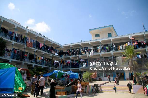 Displaced Palestinian citizens gather at the UNRWA school in Khan Yunis, after evacuating their homes that were damaged by Israeli airstrikes on...